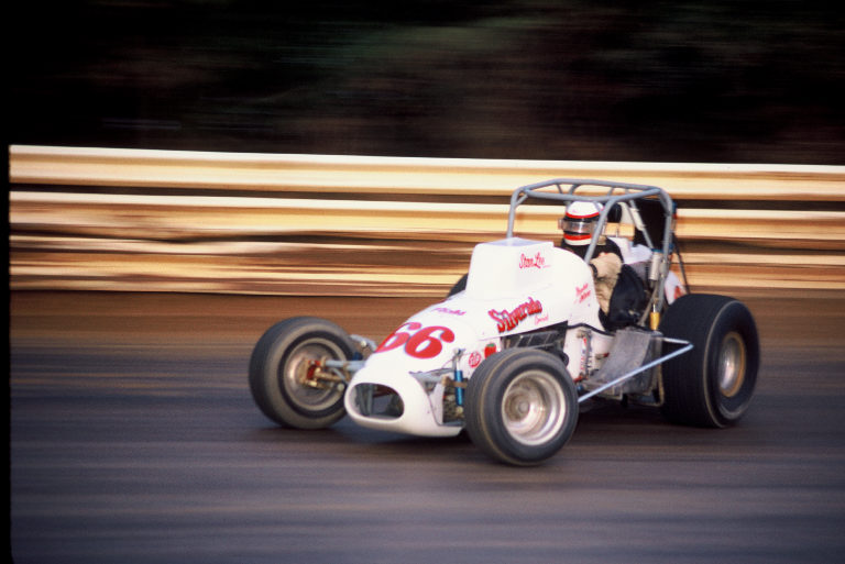 a person driving a cart racing in a dirt track