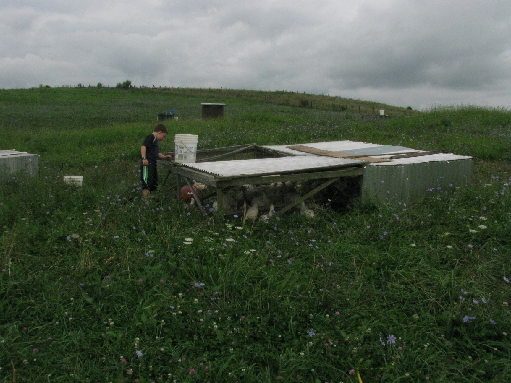 a person walking through a field near some old broken down wooden objects