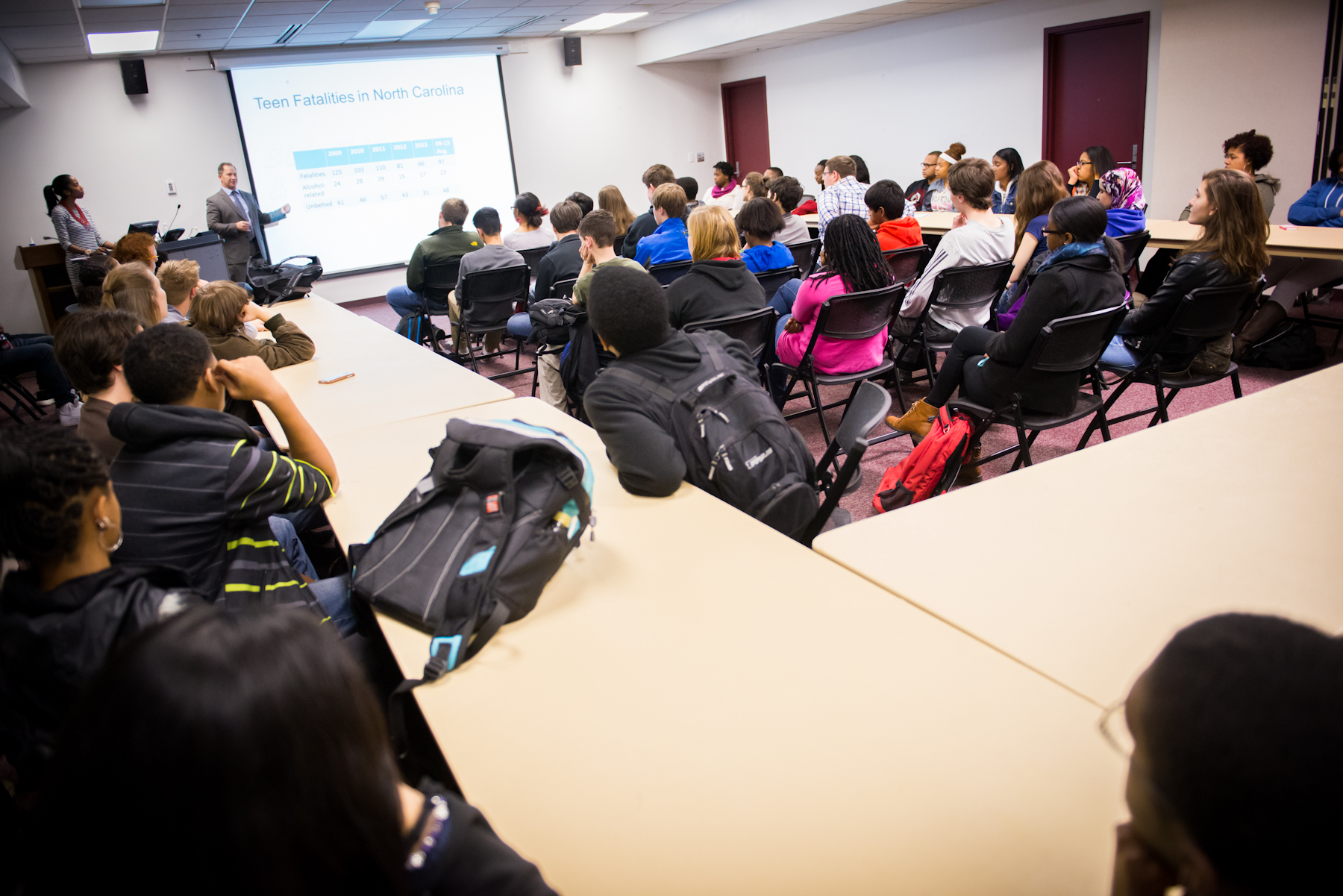 a class room with people in chairs listening to someone