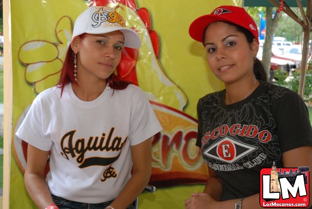 two girls in baseball caps standing by a bright sign
