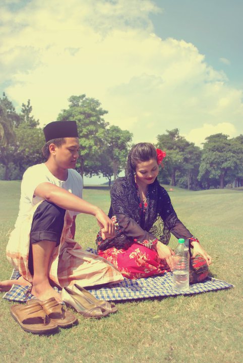 a man and woman sit on a blanket at a park