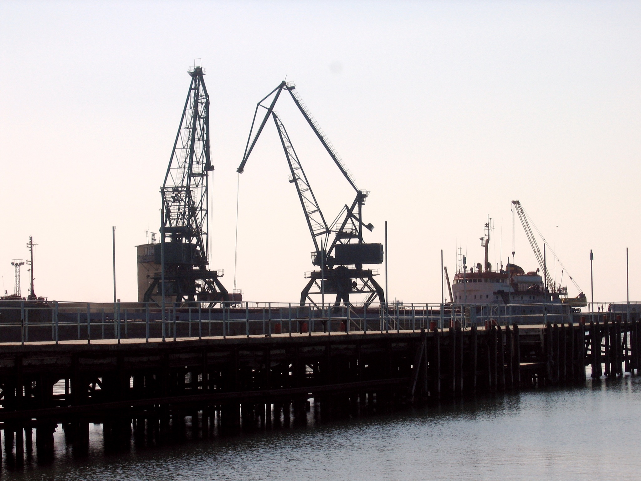 a dock with several cranes standing in the water