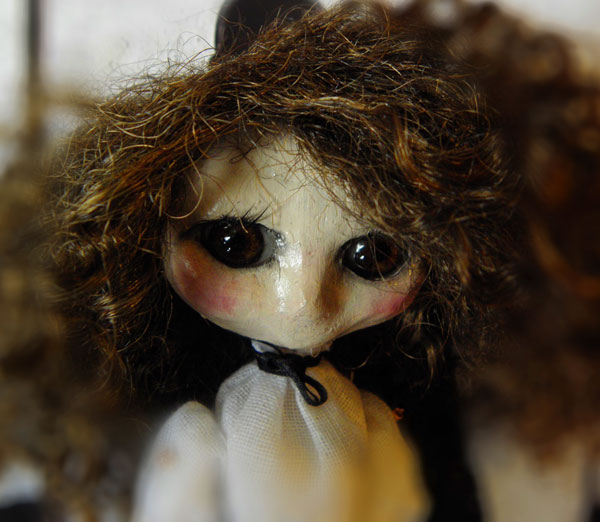 the doll has long curly hair and a white shirt