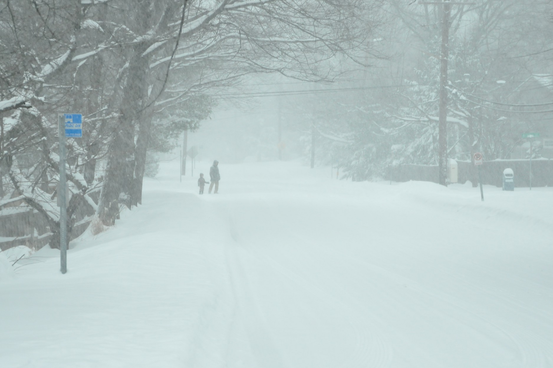 two people walking down the snow covered street