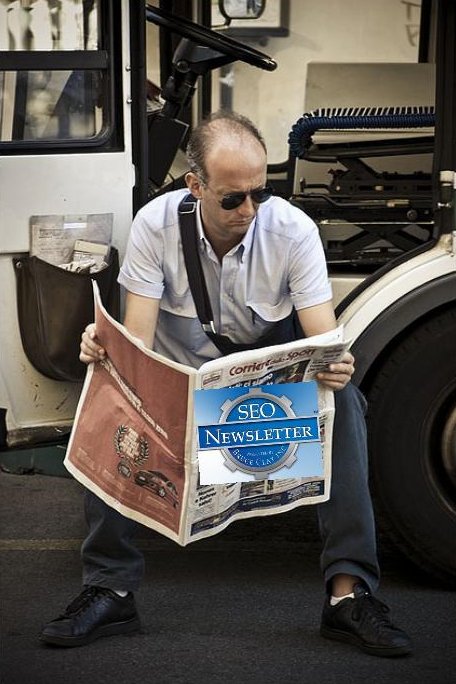 a man is reading a newspaper next to a parked bus