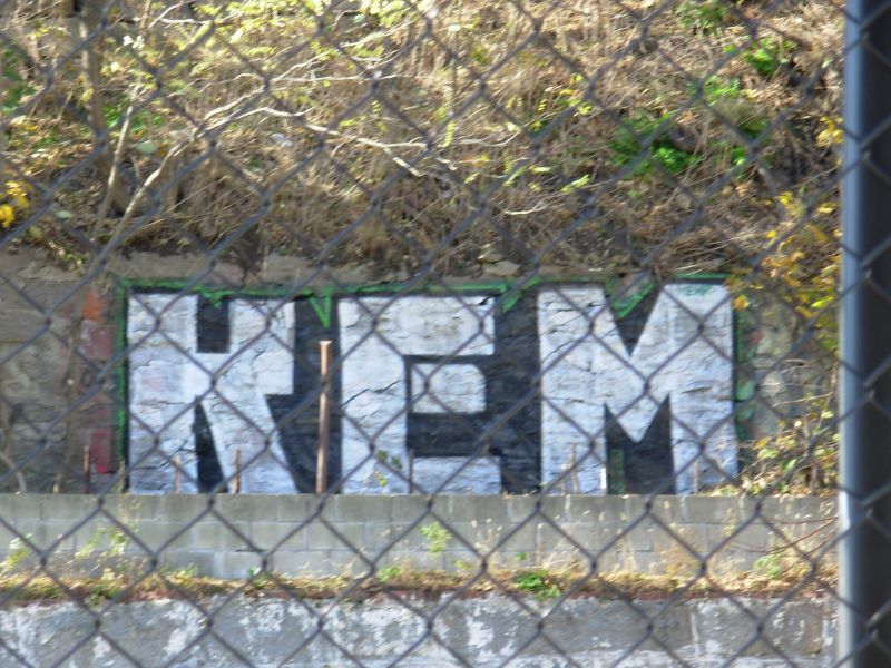 a picture of an urban area with words written on them behind a chain link fence