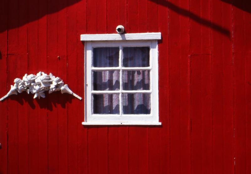 a red house with a white window and shutters