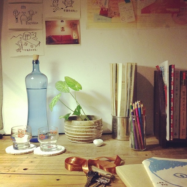 a vase, glasses, books and a plant sit on a table