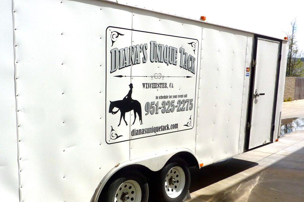 there is an trailer with the writing horse and carriage stables on the front of it