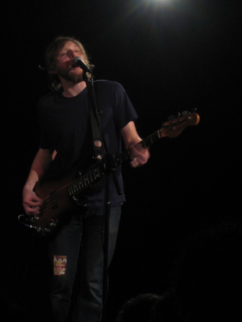 a man standing at the microphone with his guitar