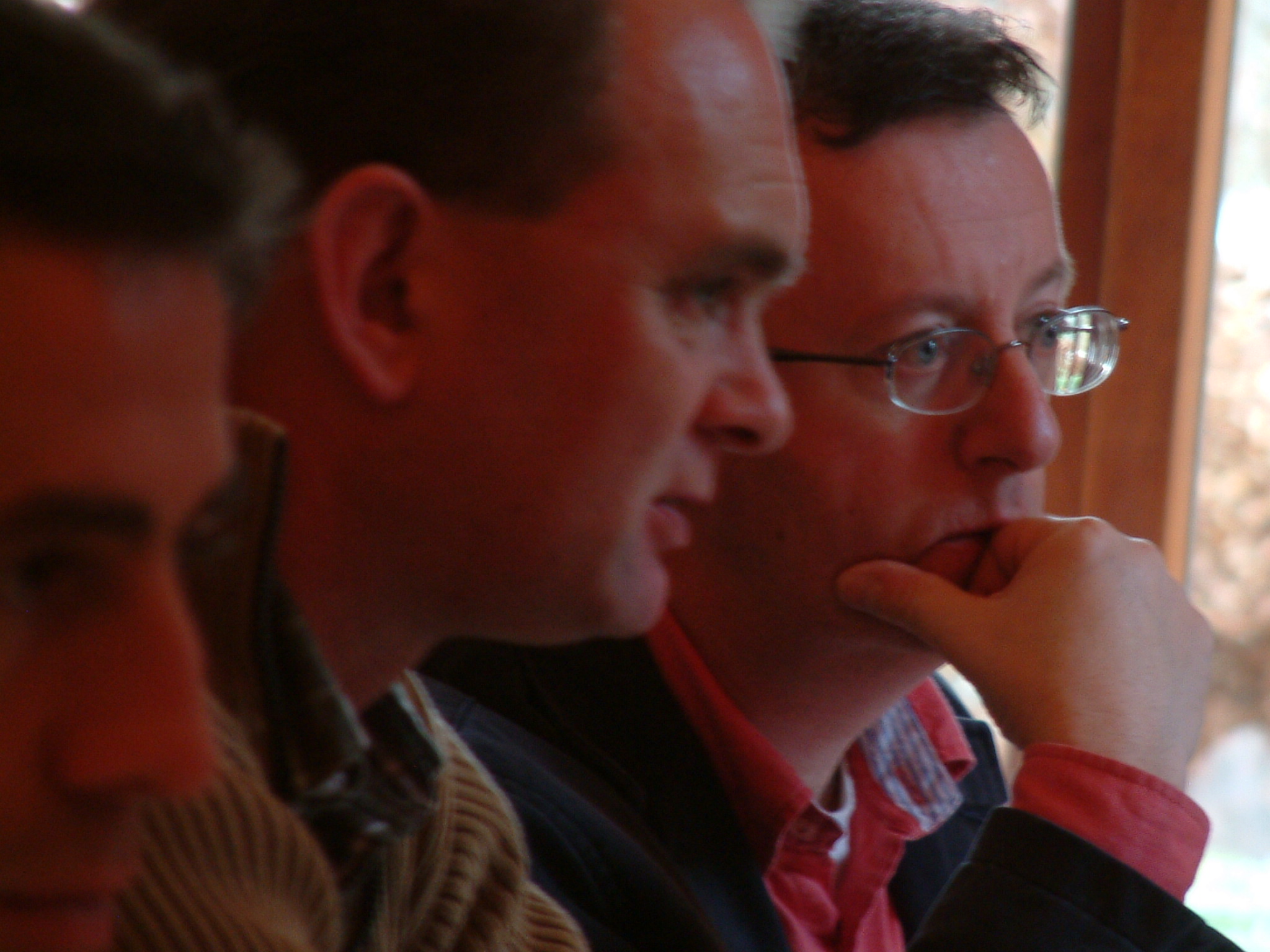 four men, one wearing glasses, are sitting