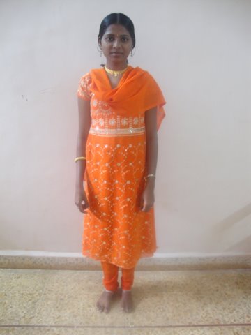 a young indian woman stands in an orange colored outfit