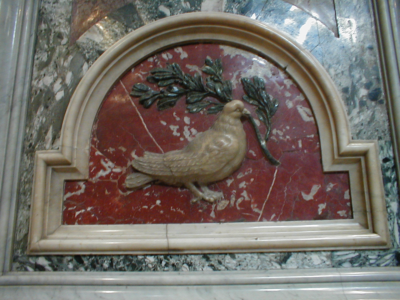 a golden bird in a frame with a sprig of holly