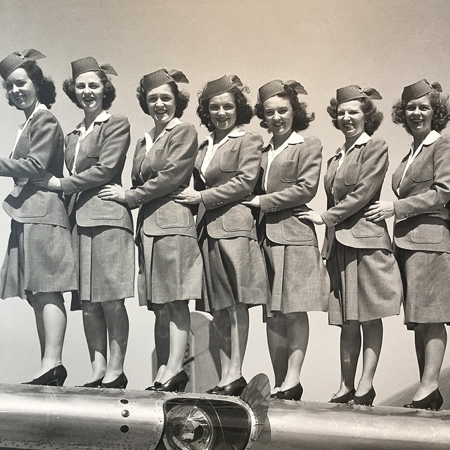 an old picture shows a group of women in front of a plane