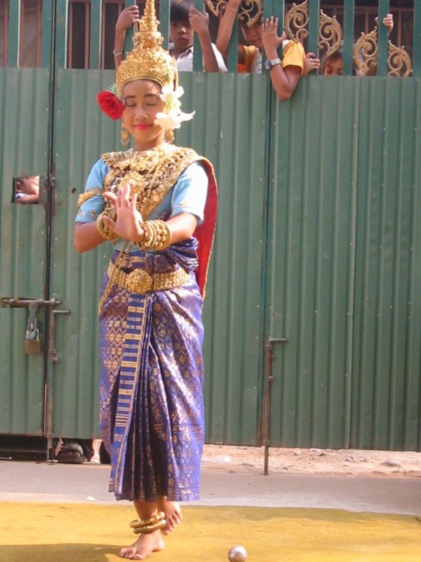a thai dancer with golden headdress and a garland on her neck