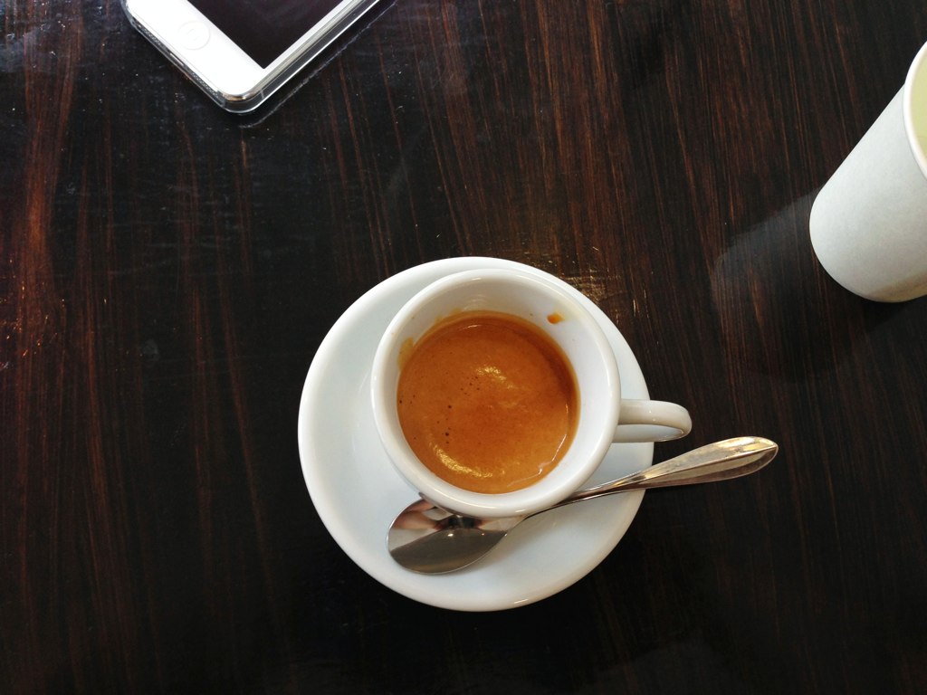 cup of coffee next to a mobile phone on a table