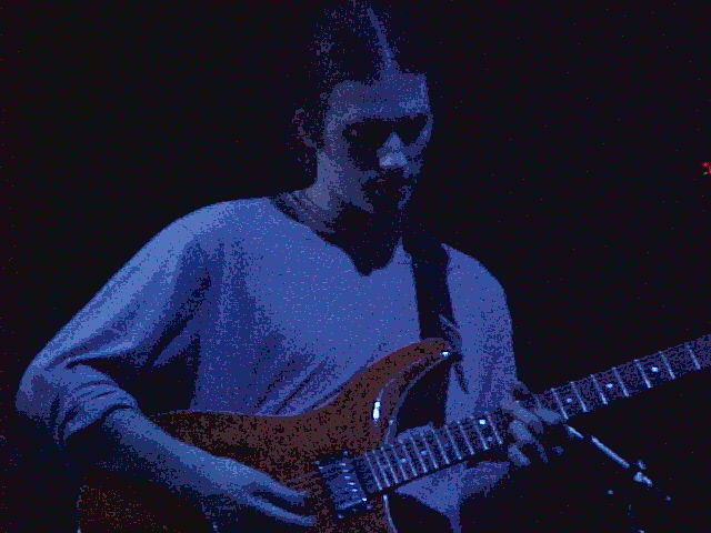 a man is playing the guitar while it is dark