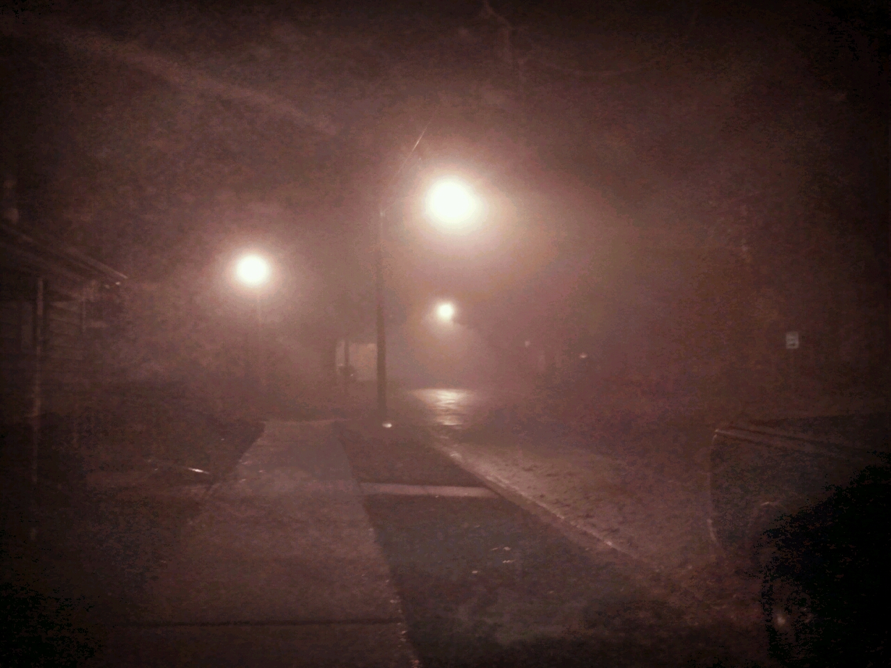 a light pole in a dark fog filled city street