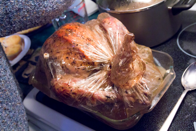 a roaster full of turkey wrapped in plastic and ready to cook