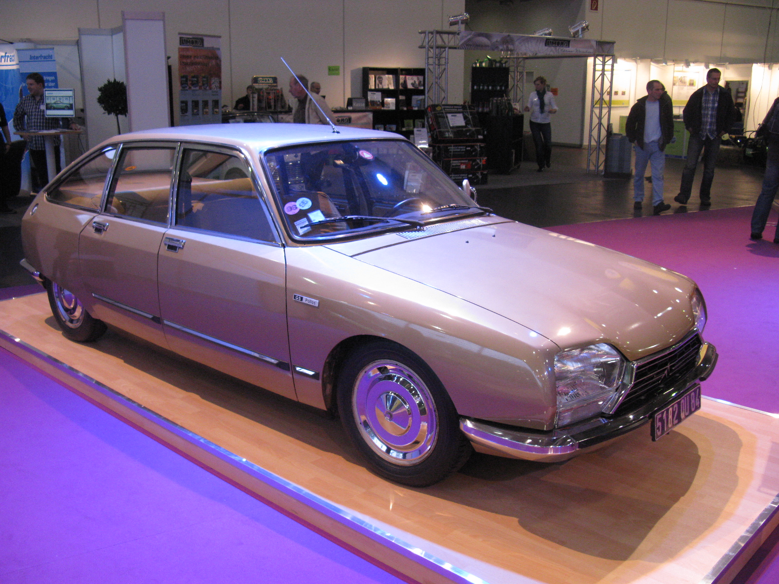 an old, silver car is sitting on display at an exhibition