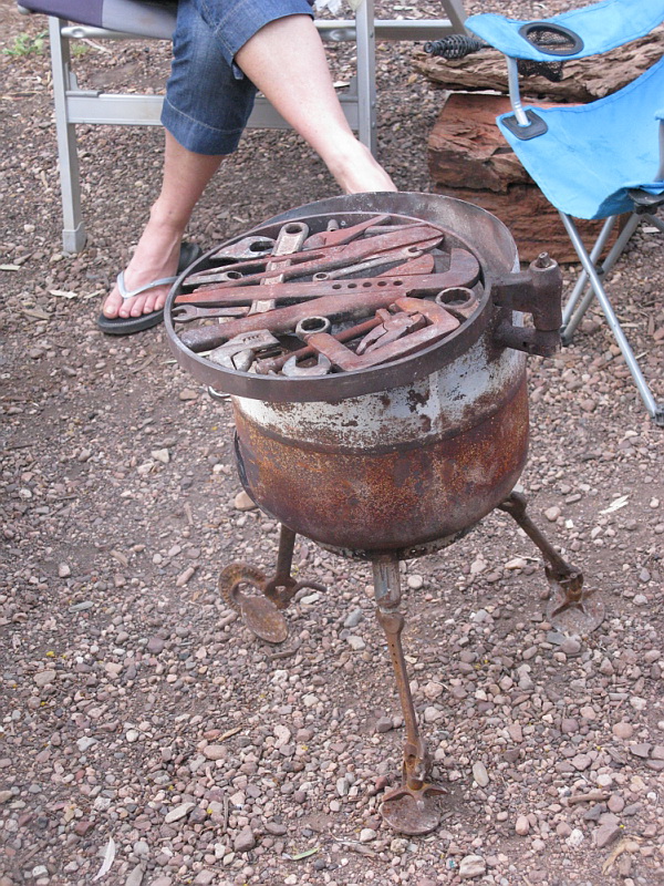 a metal fire pit sitting on top of a dirt ground