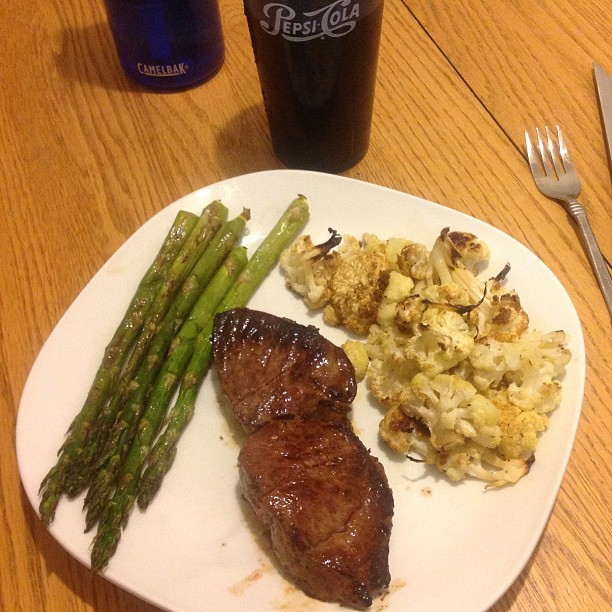 a white plate topped with steak, rice and asparagus