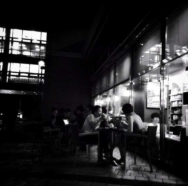 a black and white po shows people sitting in a dark cafe