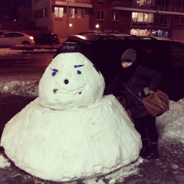 snowman made of foam sitting in front of an suv