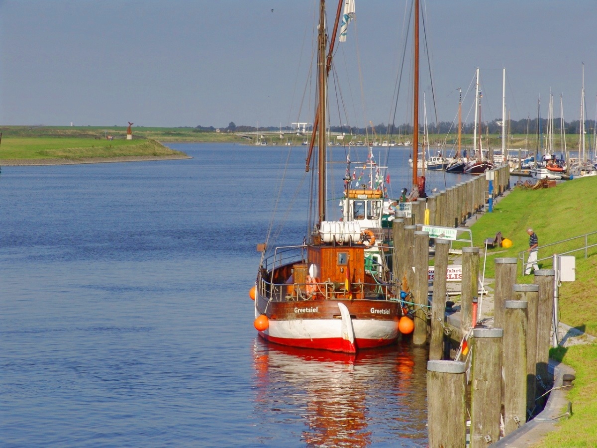 a long boat floating down a river with lots of boats on it