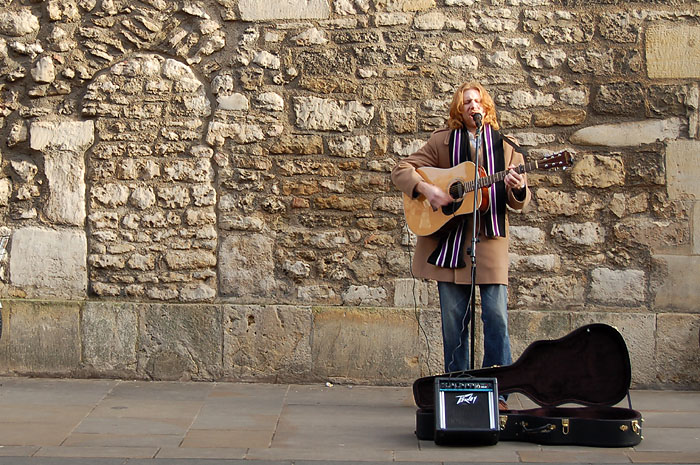 a musician on the side walk with a guitar