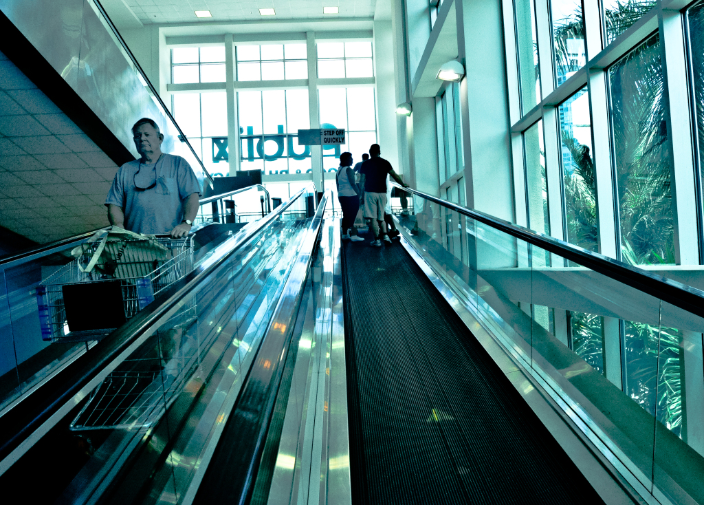three people ride an escalator in a shopping mall