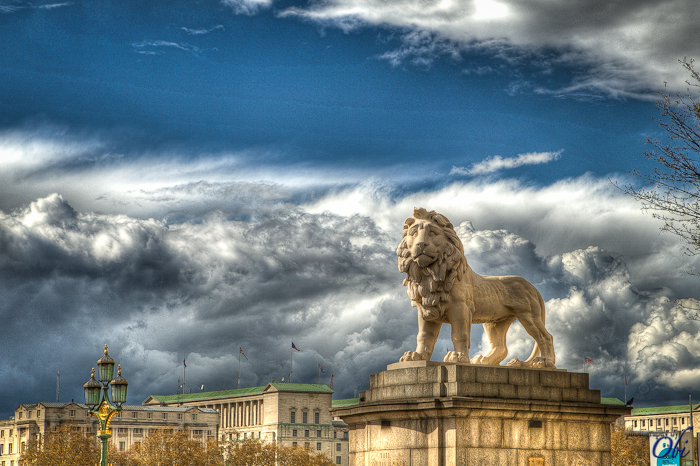 a picture of the side of a big building with a lion statue on top