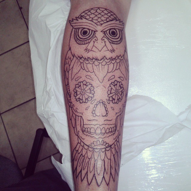 an owl with floral eyes is seen on the back of a human's leg