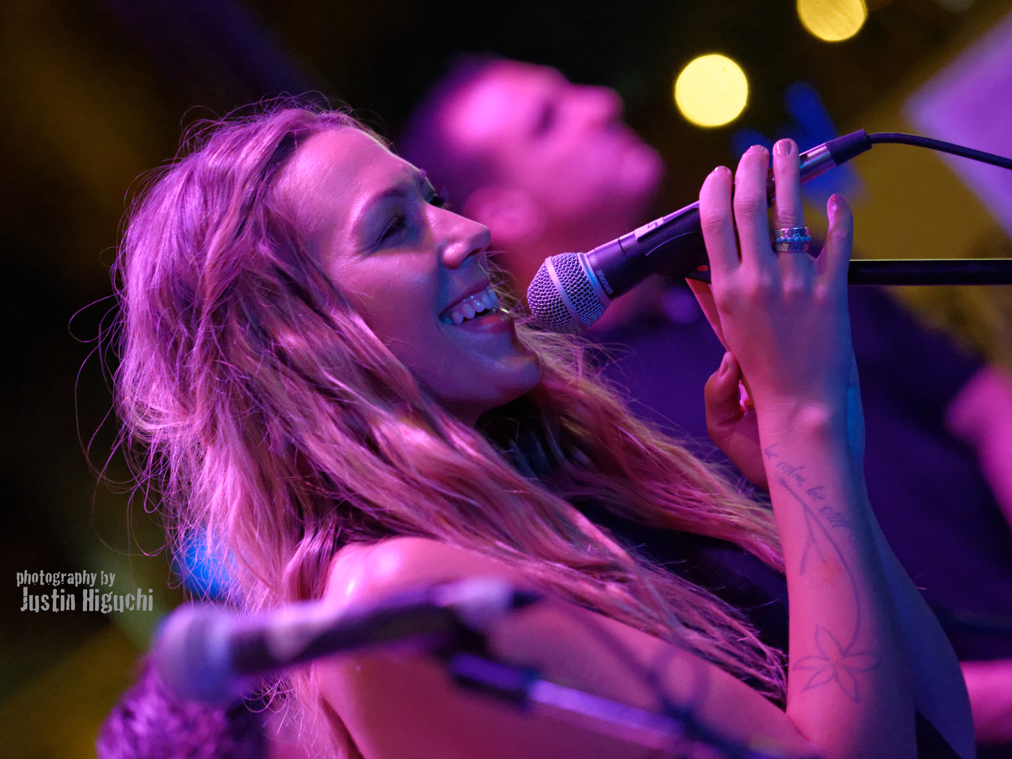 a woman sings into a microphone while on stage