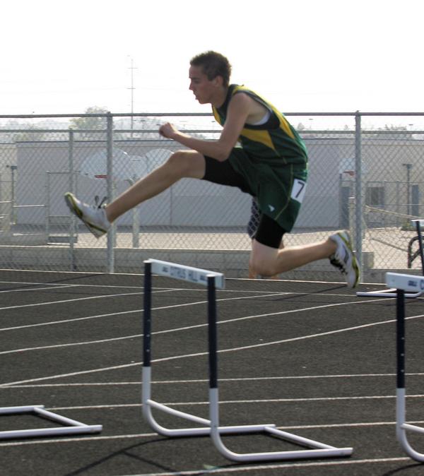 a young man jumps over the barrier in a hurdle