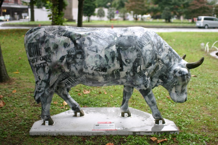 a large bull statue stands on the grass