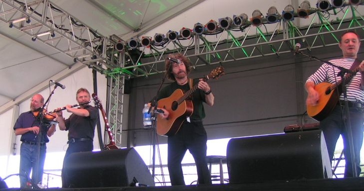 several men with instruments performing on stage at an outdoor event