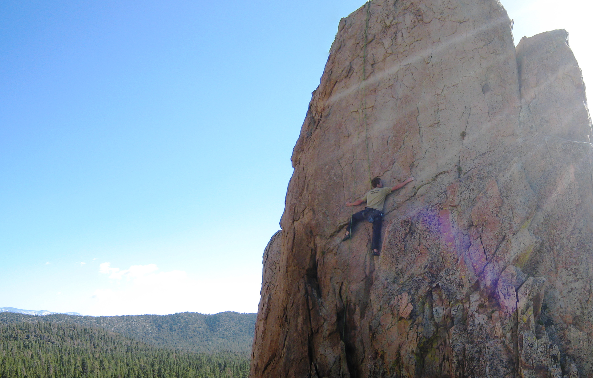 person standing at the bottom of the rock face on a sunny day