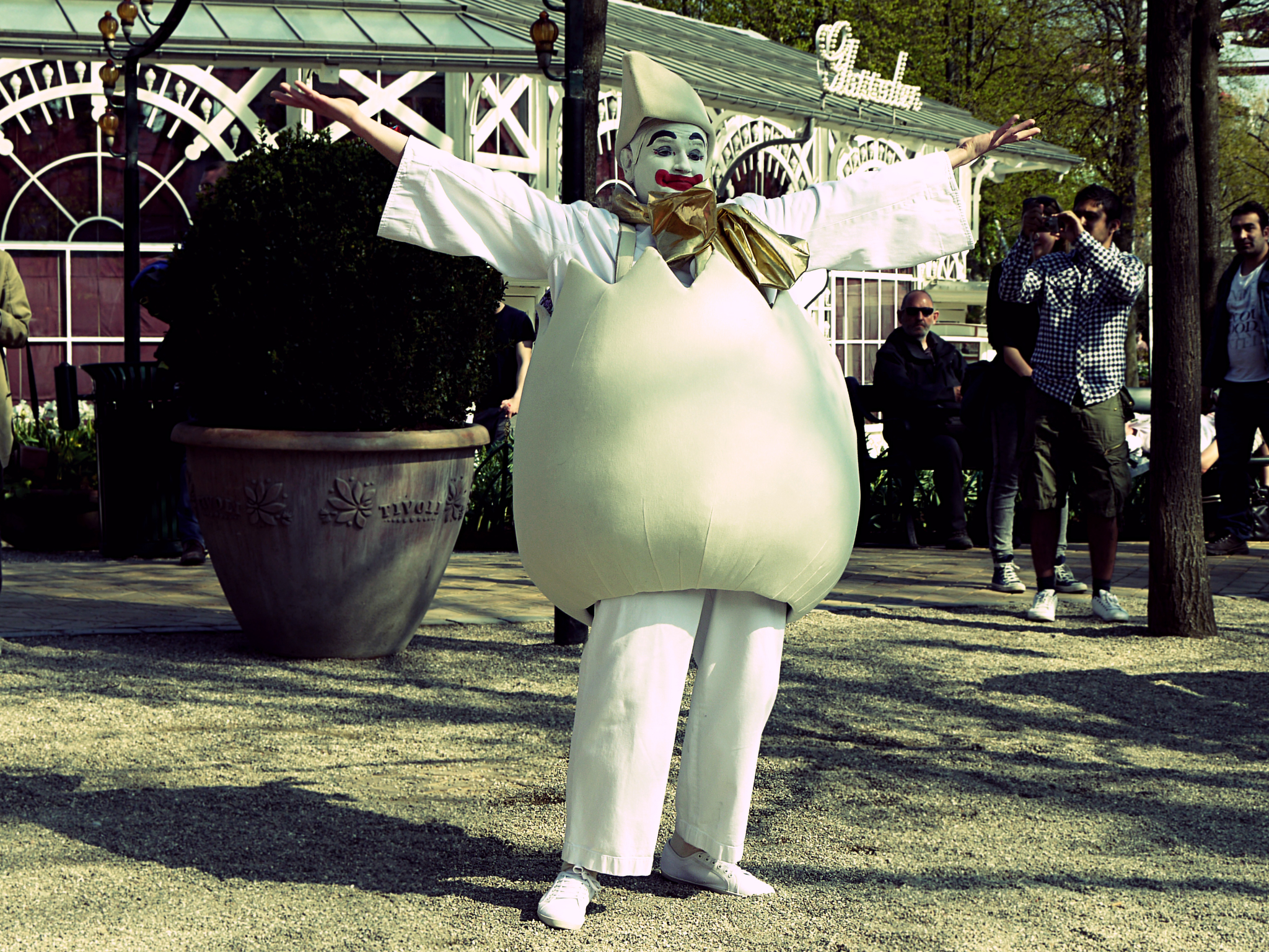 large white man in a full costume stands in the park