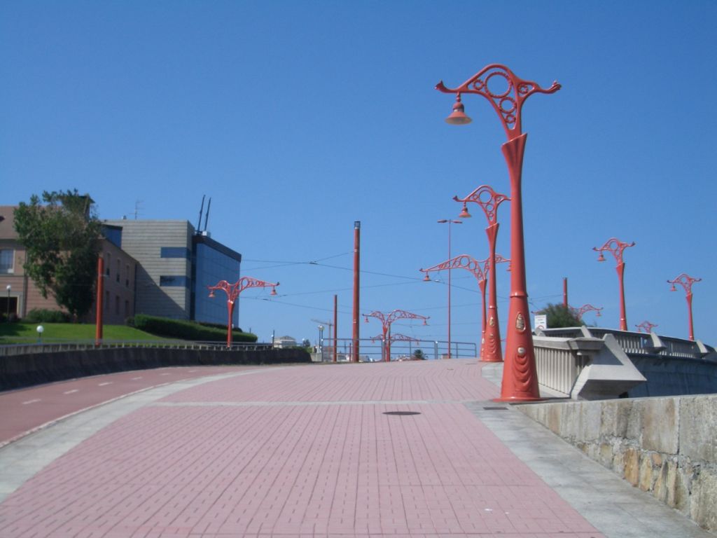 a red road is lined with lamps and poles