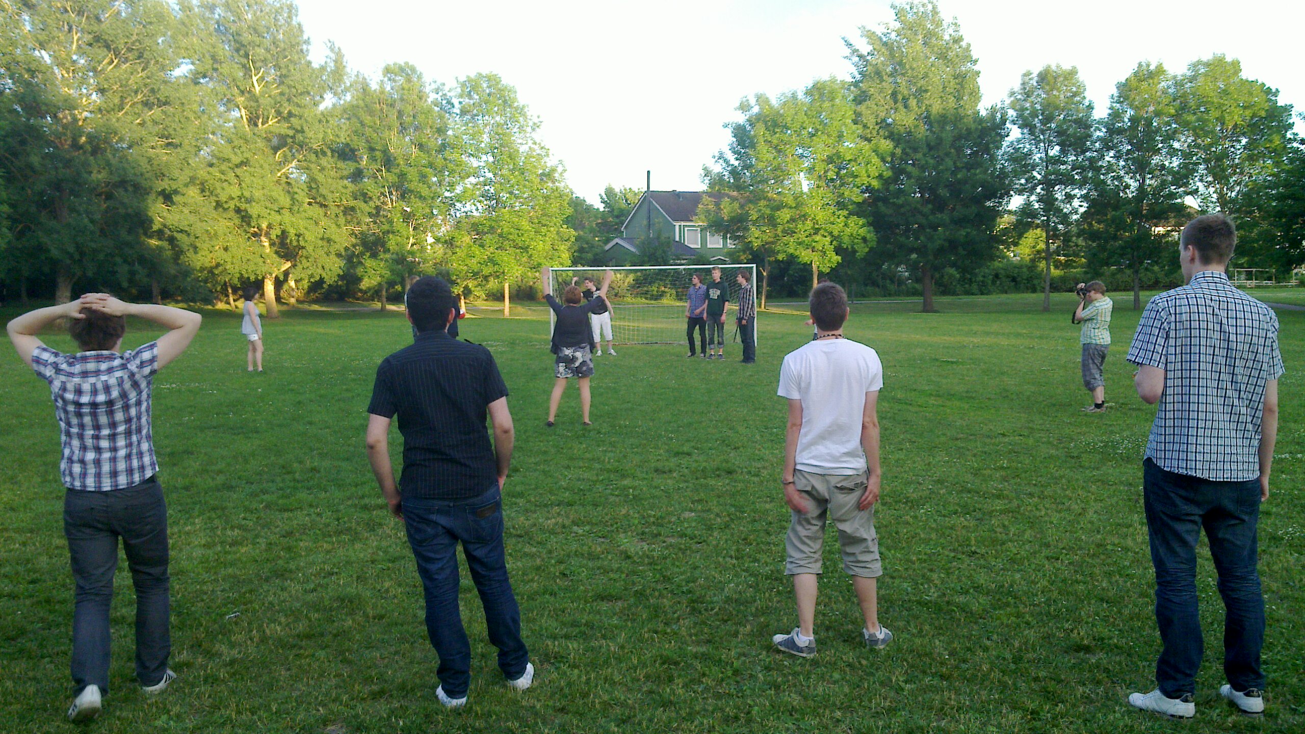 men play soccer in the grass with a group of others