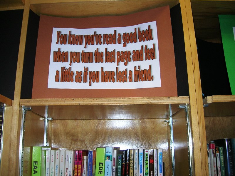 several books on shelves with a sign on top