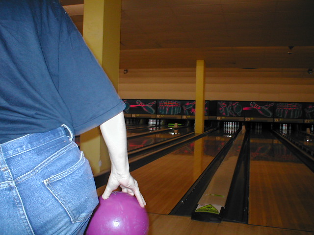 someone bowling and holding a pink ball