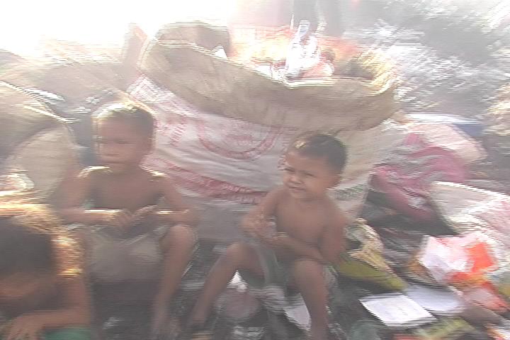 two small children sit on a floor that has been piled high in it