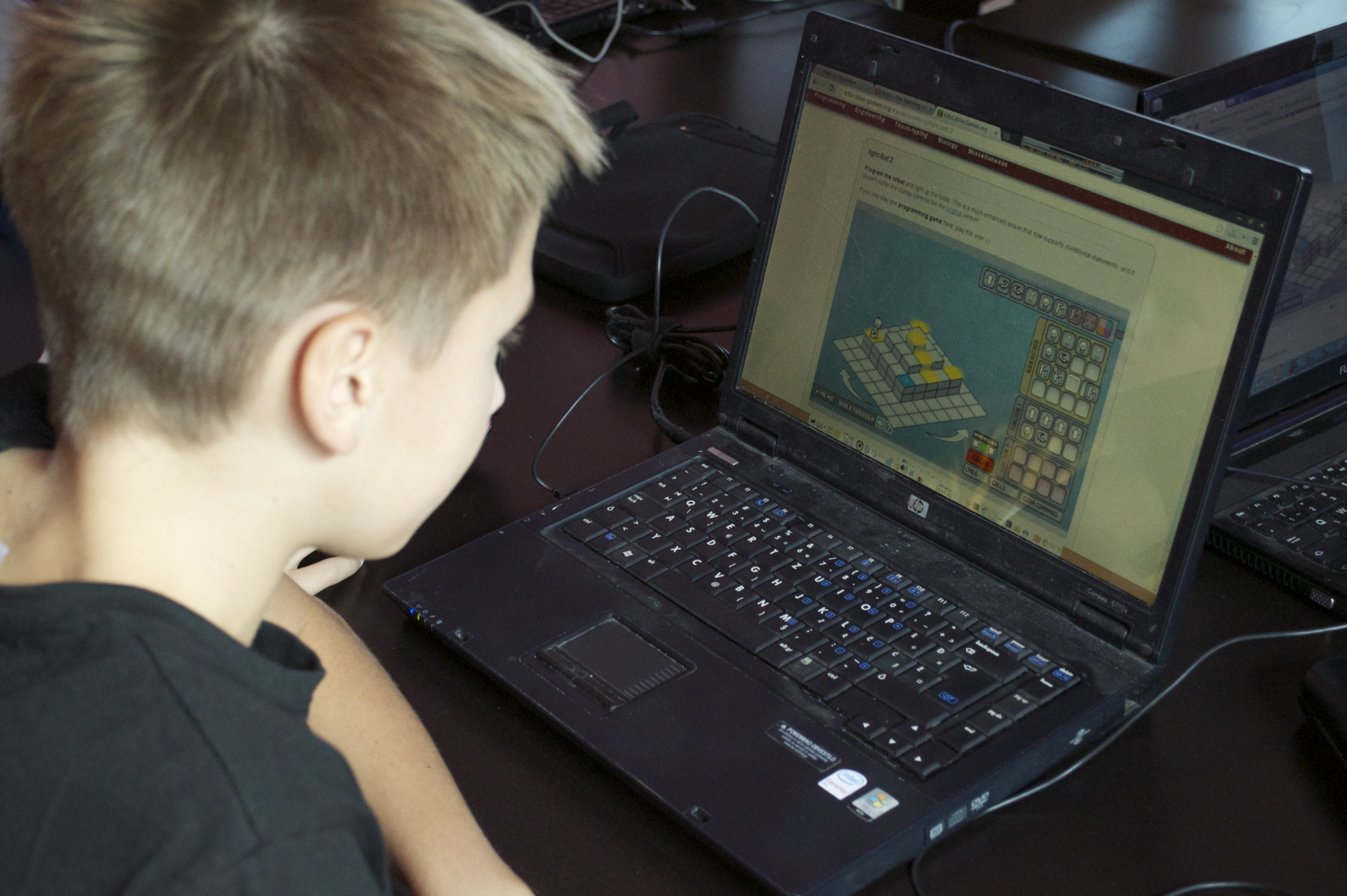 a boy at a desk playing with a laptop computer