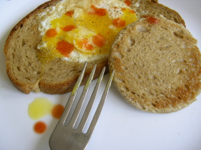 a fork resting next to some bread with eggs in it