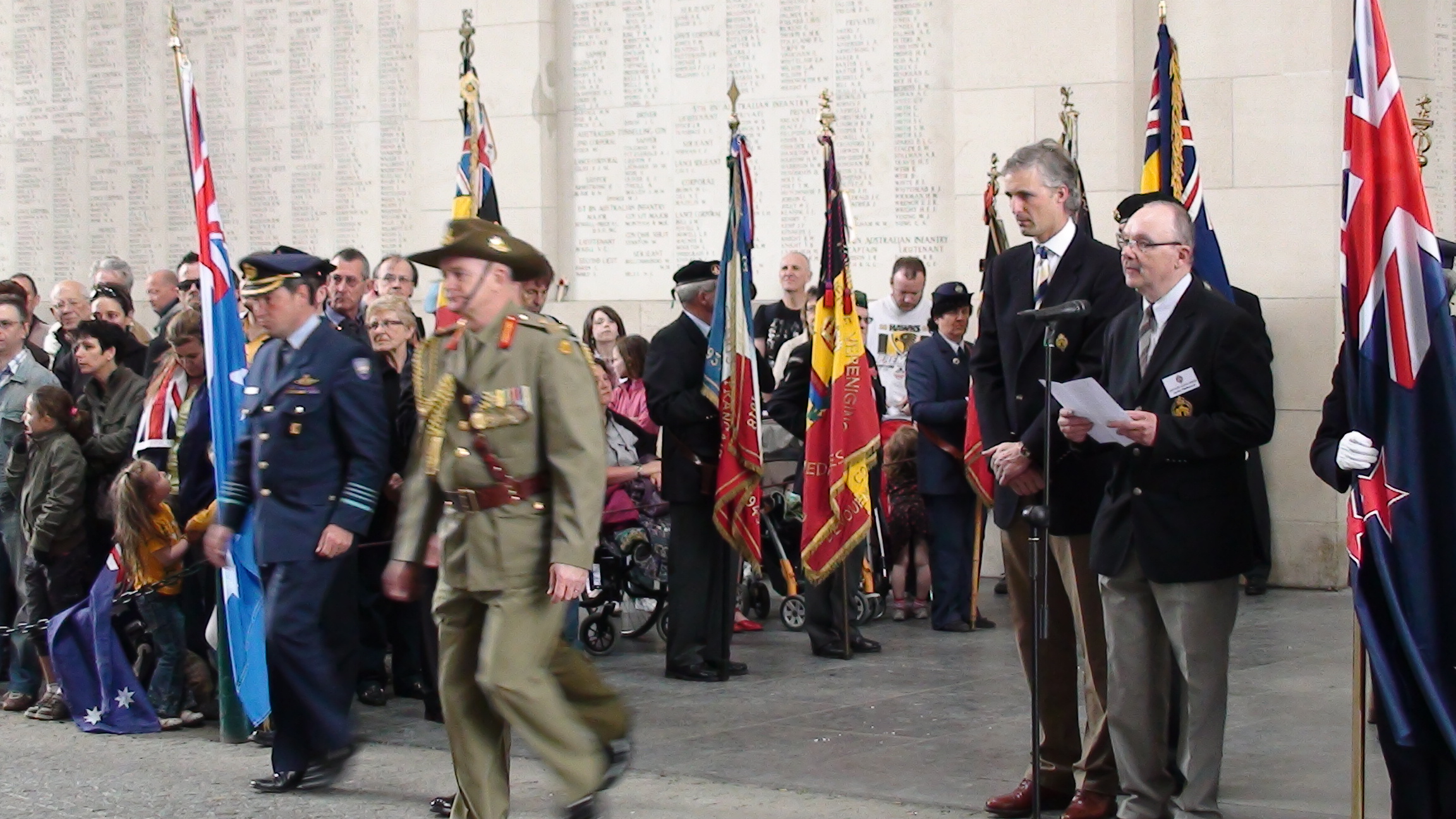 several men in uniforms walking through an outdoor area with flags