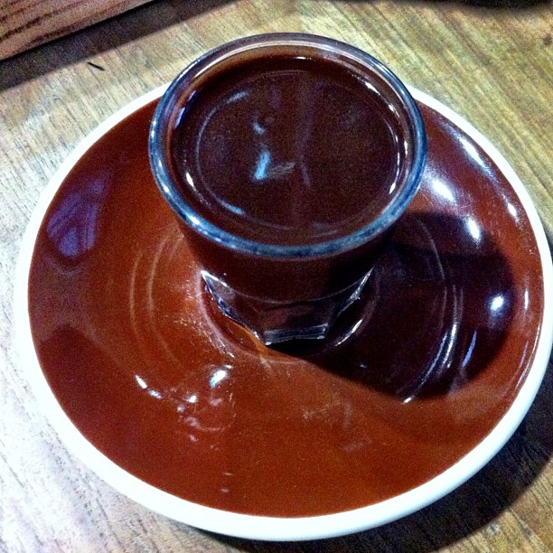 a sauce in a small dish with an overflowing brown liquid