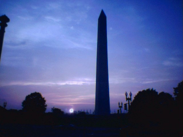 two tall obelisk with street lights, some lights and trees