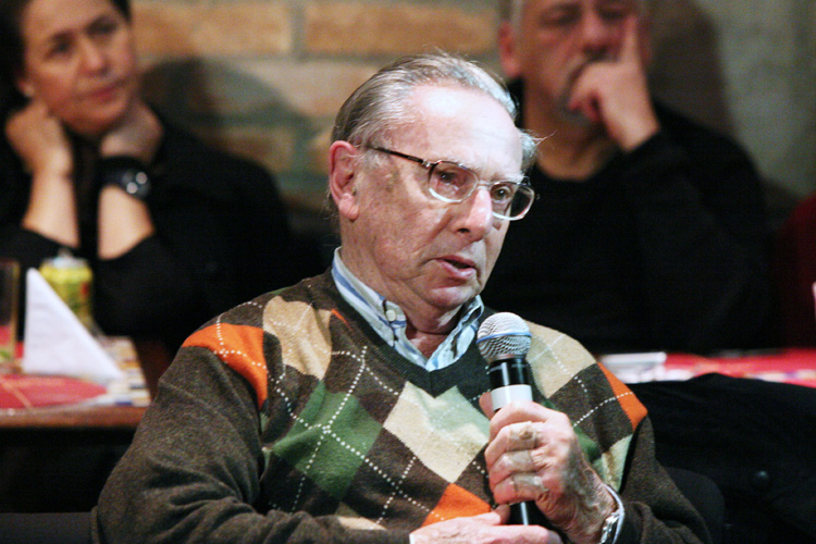 a man in plaid sweater sitting with microphone in front of him